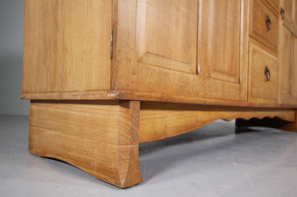 A light oak dresser base from the 1930s featuring a central stack of four drawers flanked by two panelled cupboard doors with brass ring handles. View VII