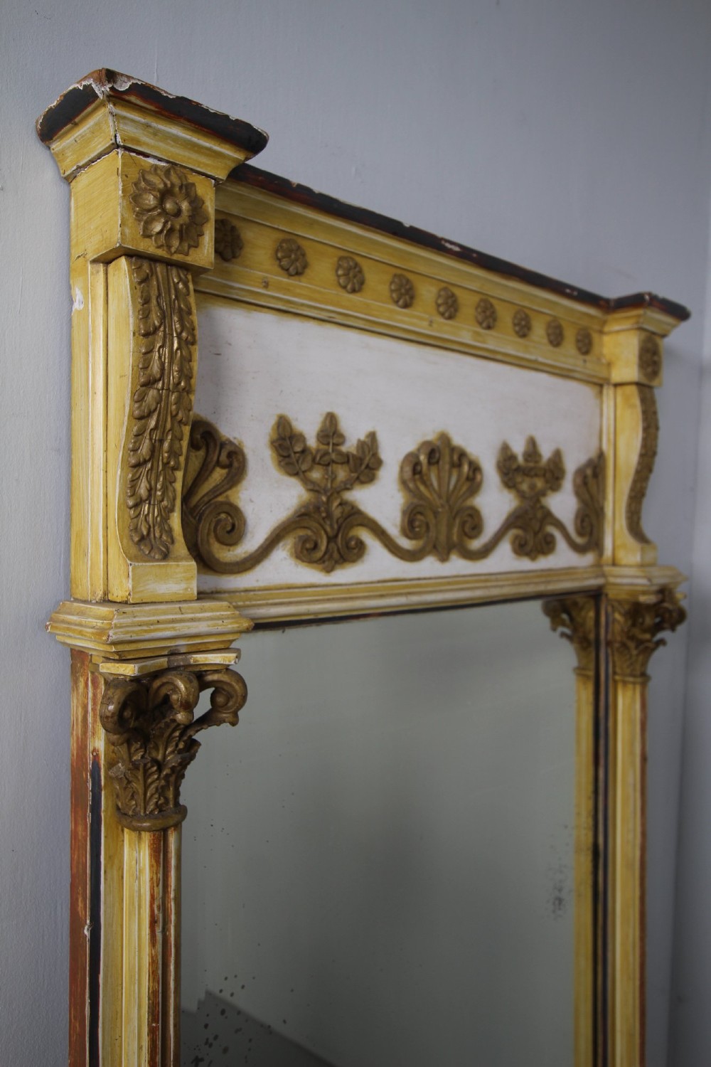 A tall nineteenth-century English Regency pier mirror featuring a cream and gilt frame flanked by fluted Corinthian columns and a decorated frieze. View V