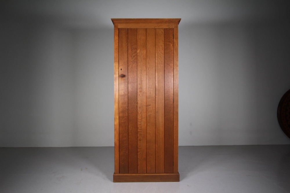 A tall single-door solid oak cupboard featuring vertical plank door construction, a wooden knob handle, and a simple plinth base. View IV