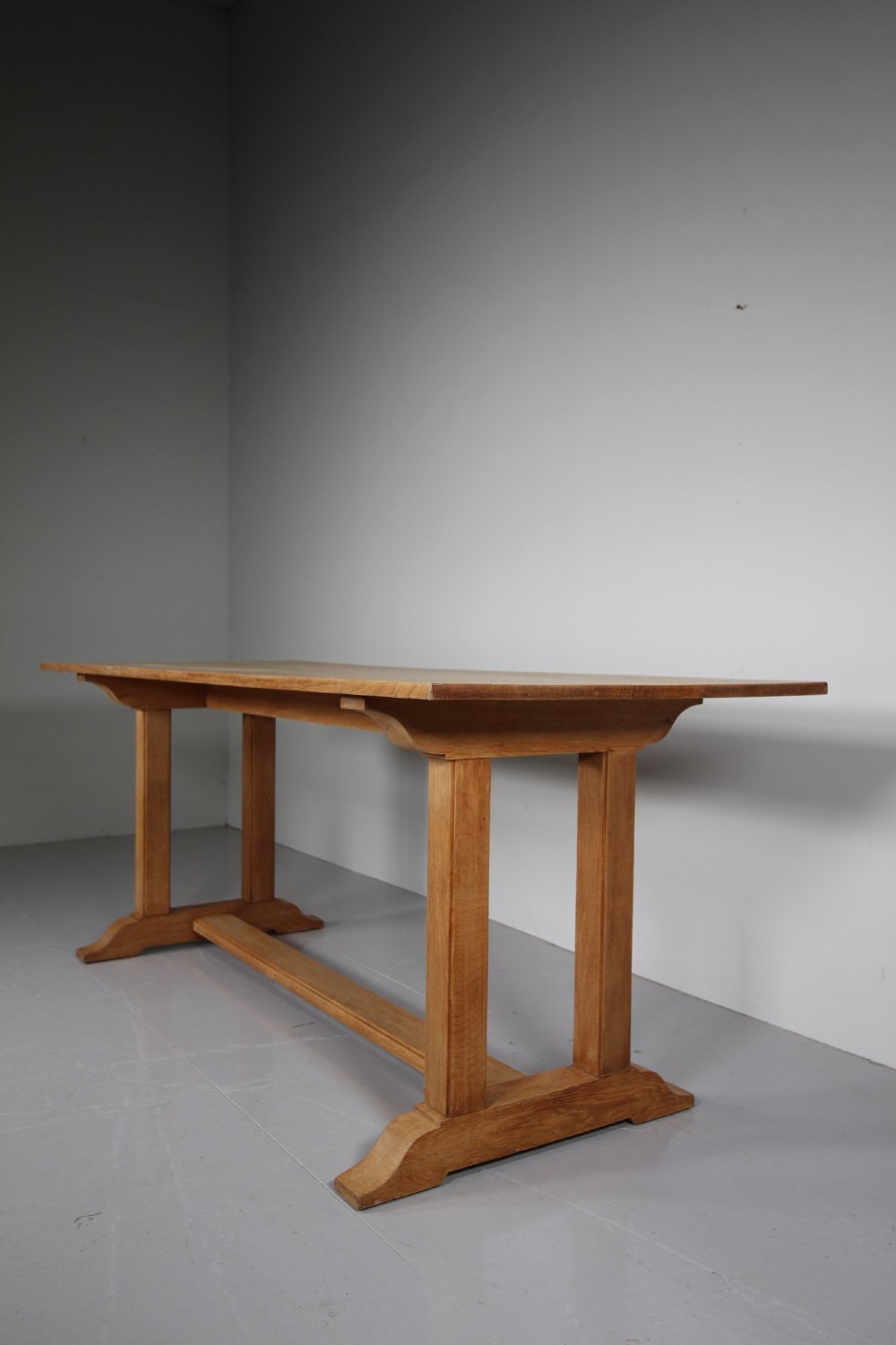 A 1930s solid oak refectory dining table featuring a plain rectangular top, twin upright trestle end supports, and a low central stretcher beam. View II