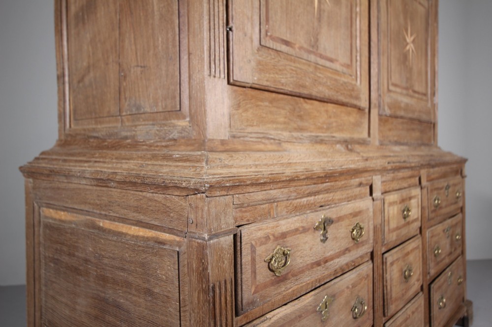 A tall two-part 17th-century Welsh oak press cupboard featuring panelled doors with star inlay motifs above a chest base with multiple drawers. View III