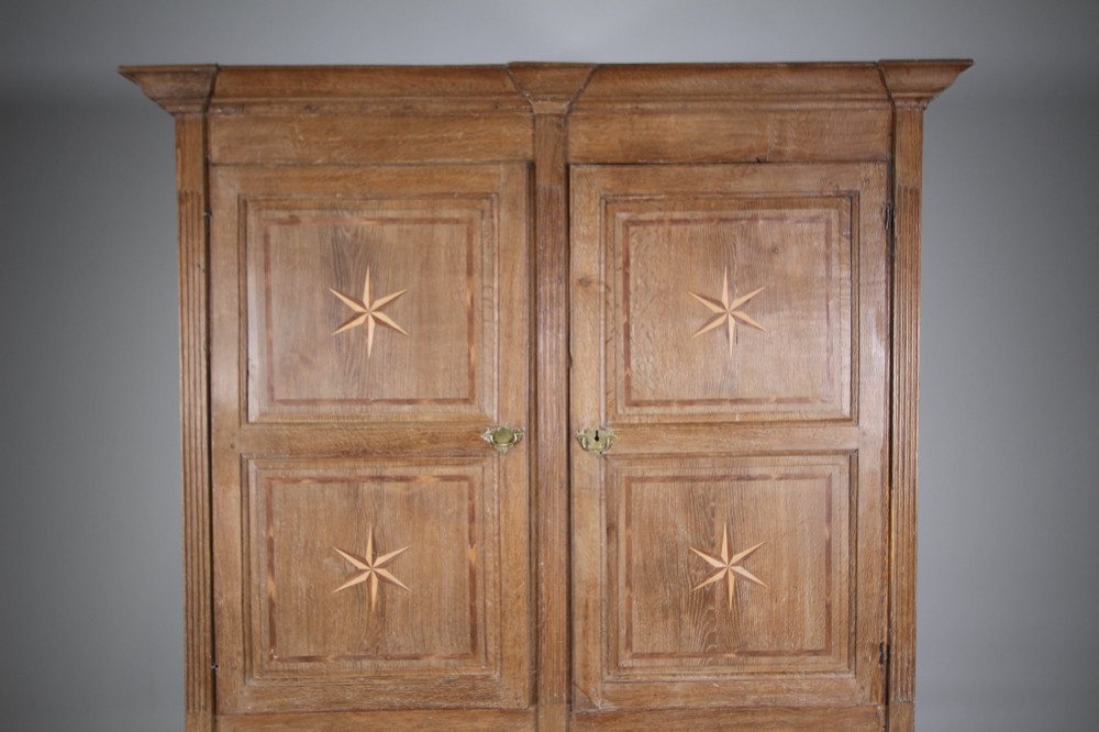 A tall two-part 17th-century Welsh oak press cupboard featuring panelled doors with star inlay motifs above a chest base with multiple drawers. View IV