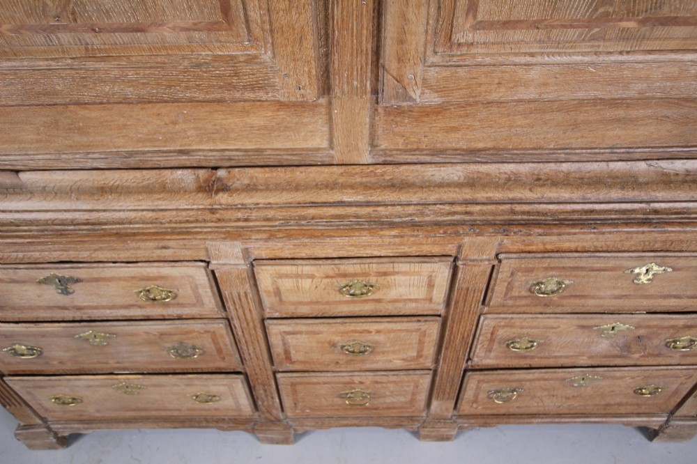 A tall two-part 17th-century Welsh oak press cupboard featuring panelled doors with star inlay motifs above a chest base with multiple drawers. View X