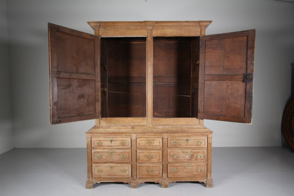 A tall two-part 17th-century Welsh oak press cupboard featuring panelled doors with star inlay motifs above a chest base with multiple drawers. View XII
