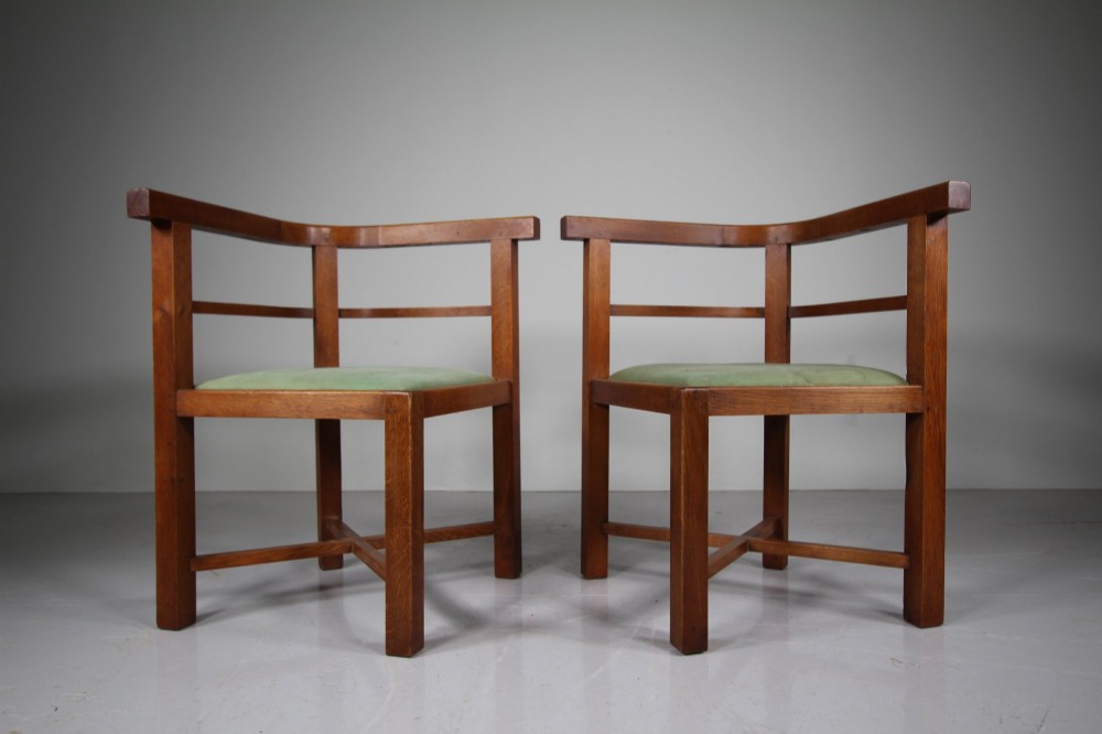 A square natural oak dining table surrounded by four matching curved-back armchairs with green upholstered seats. View III
