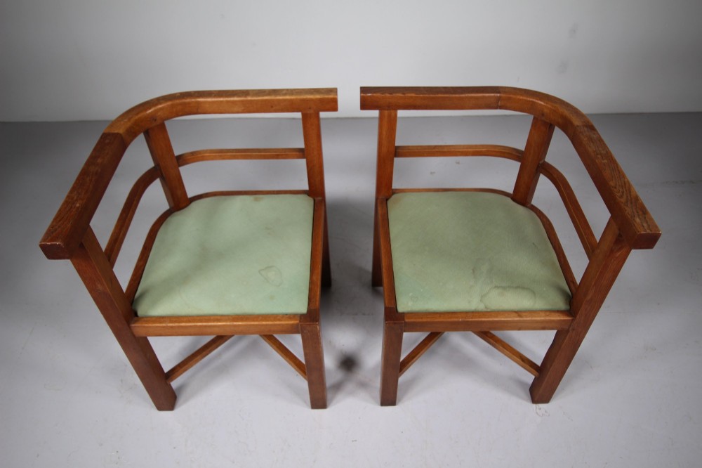 A square natural oak dining table surrounded by four matching curved-back armchairs with green upholstered seats. View IV