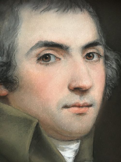 fig 2. An oval portrait of a gentleman wearing a brown jacket, set within a square gilded spandrel frame and dark outer ebonised border.