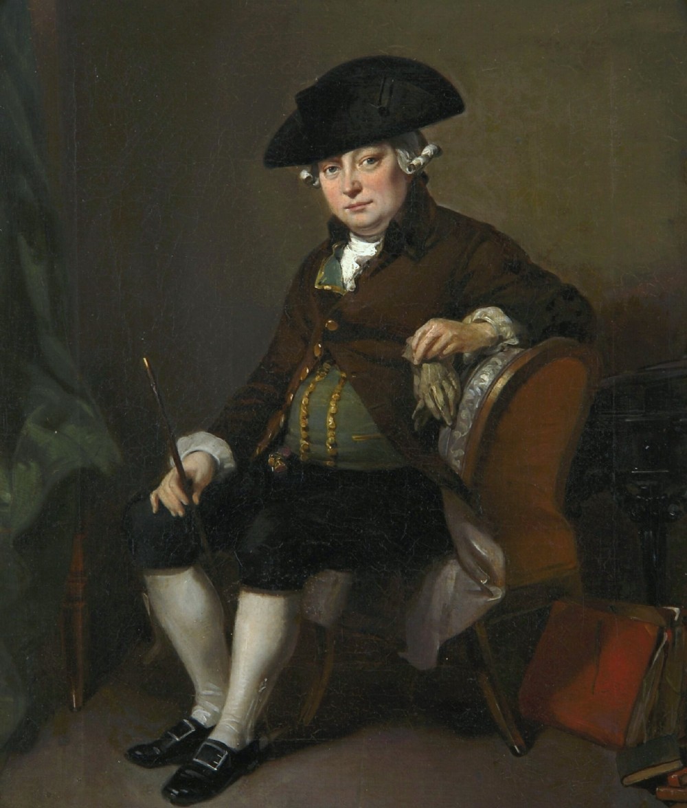 An antique oil painting depicting a seated actor in 18th-century attire holding a cane, displayed inside an elaborate gold gilt frame. View II