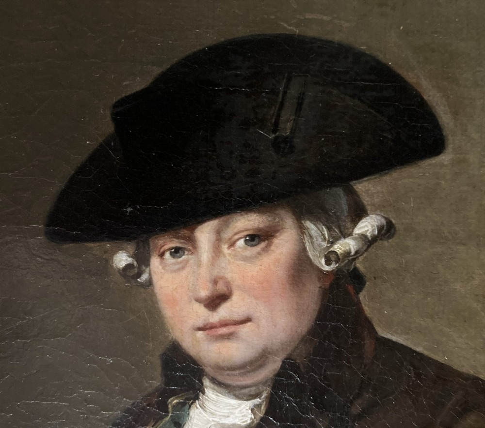 An antique oil painting depicting a seated actor in 18th-century attire holding a cane, displayed inside an elaborate gold gilt frame. View V