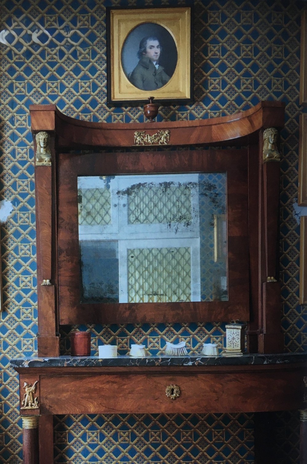 An oval portrait of a gentleman wearing a brown jacket, set within a square gilded spandrel frame and dark outer ebonised border. View IV