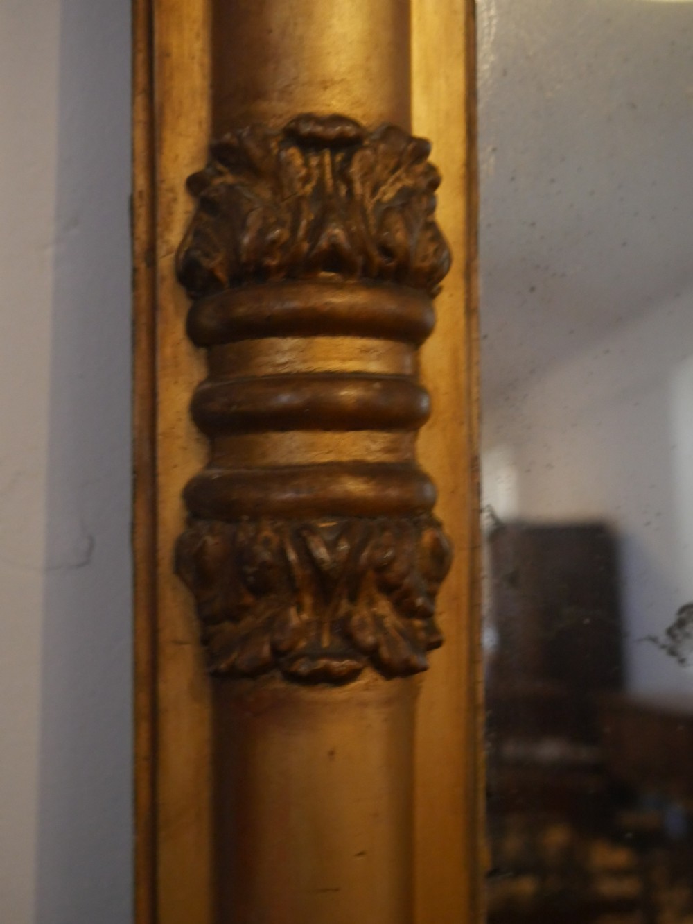 A broad rectangular late Regency giltwood overmantel mirror featuring a reeded frame with carved corner rosettes and central moulding accents. View II