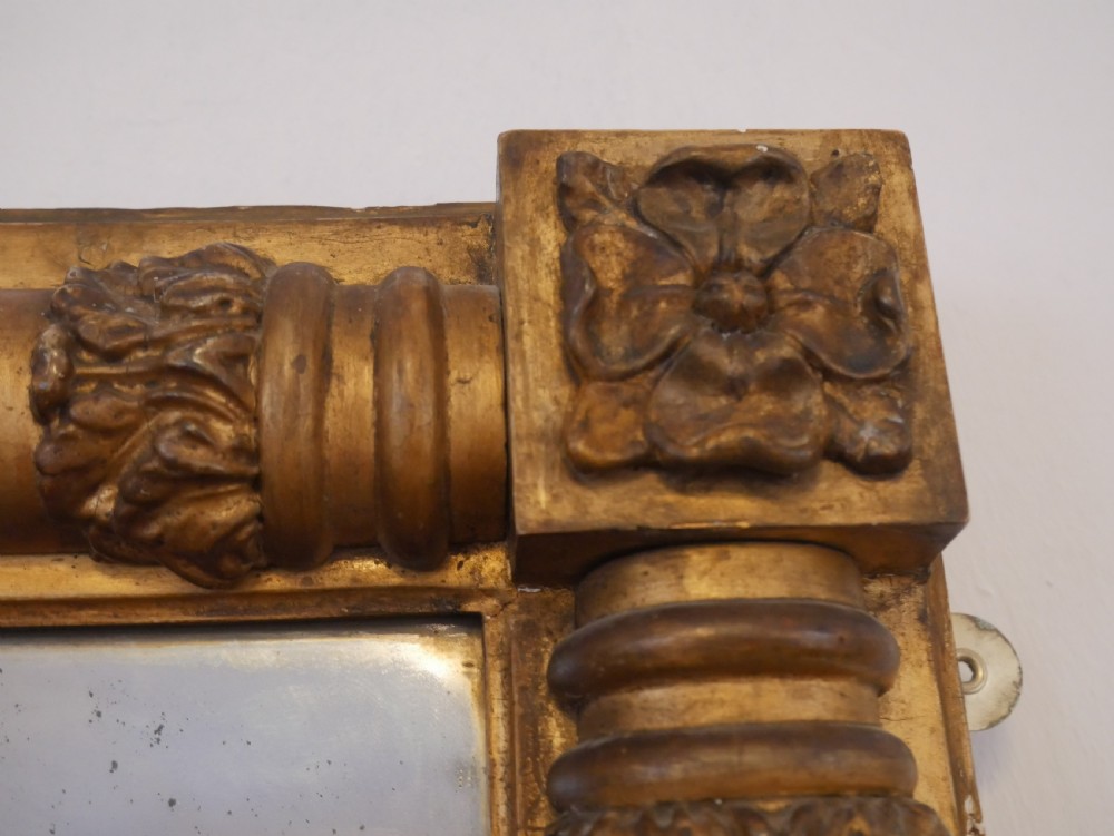 A broad rectangular late Regency giltwood overmantel mirror featuring a reeded frame with carved corner rosettes and central moulding accents. View VIII
