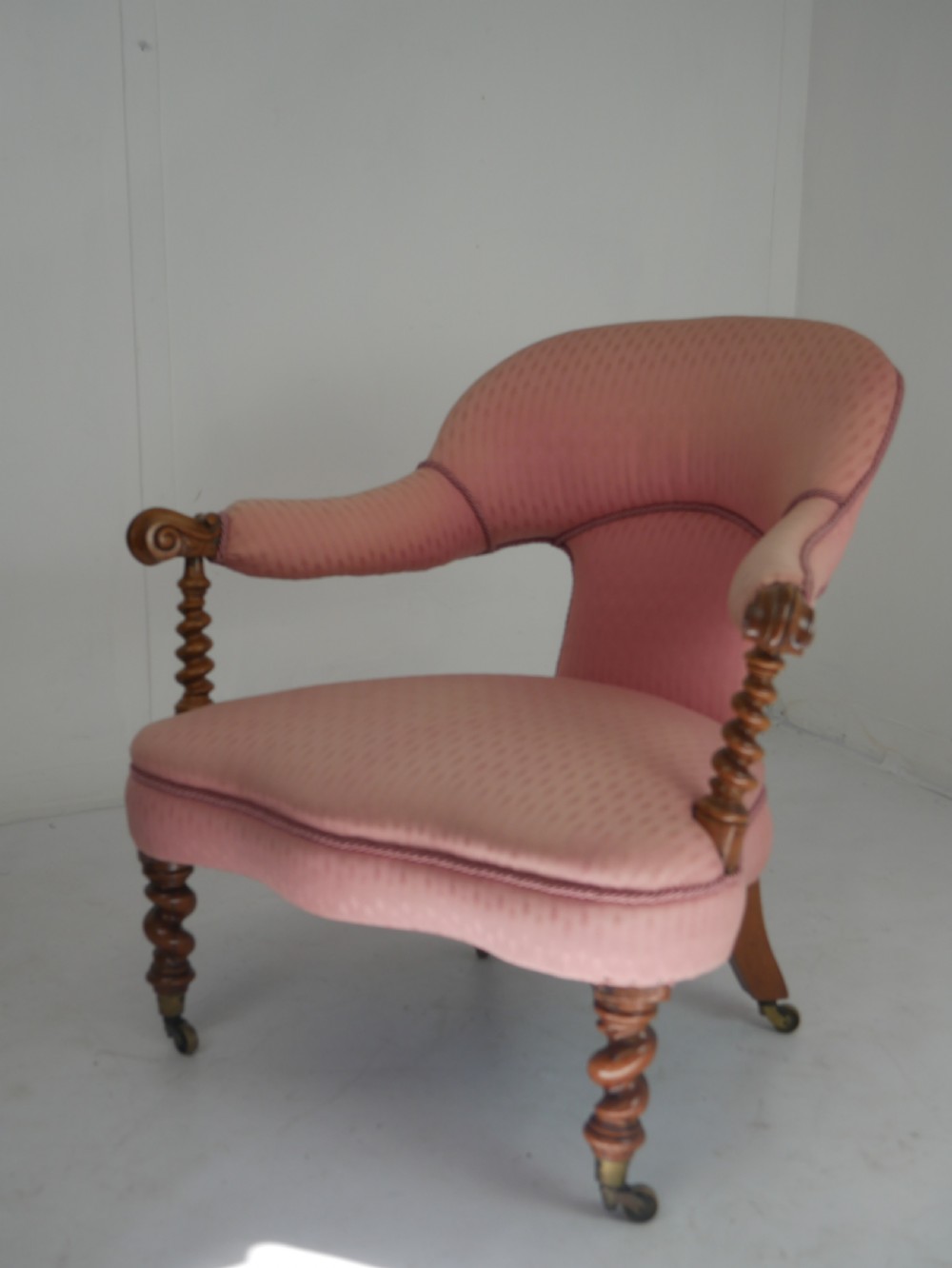 A Victorian armchair upholstered in dusty pink patterned fabric featuring carved walnut barley-twist legs and arm supports set on brass castors. View III