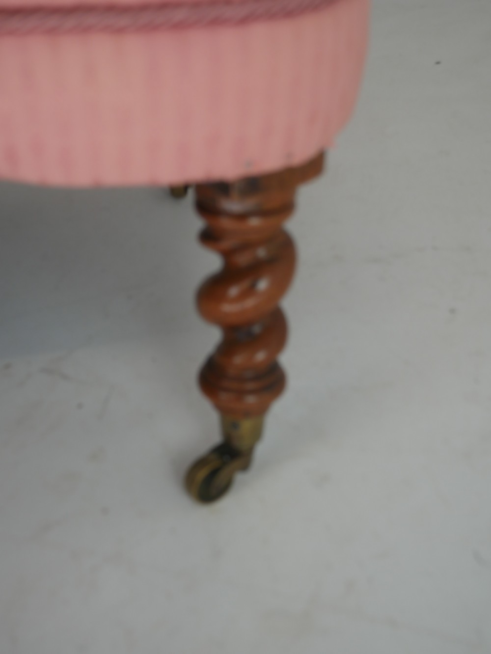 A Victorian armchair upholstered in dusty pink patterned fabric featuring carved walnut barley-twist legs and arm supports set on brass castors. View V