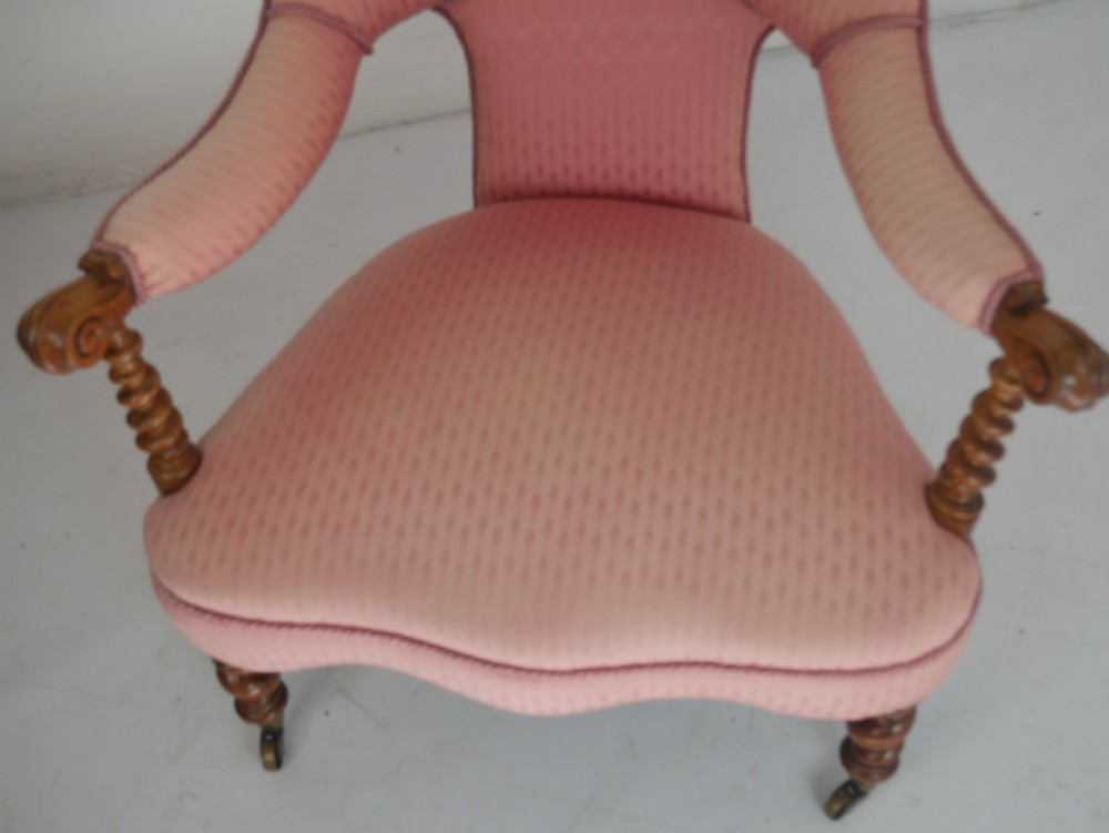 A Victorian armchair upholstered in dusty pink patterned fabric featuring carved walnut barley-twist legs and arm supports set on brass castors. View VII