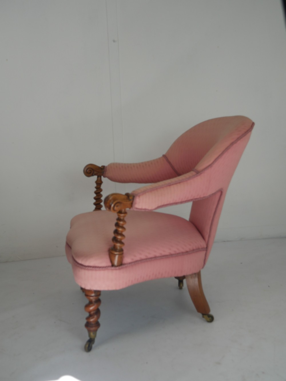 A Victorian armchair upholstered in dusty pink patterned fabric featuring carved walnut barley-twist legs and arm supports set on brass castors. View IX