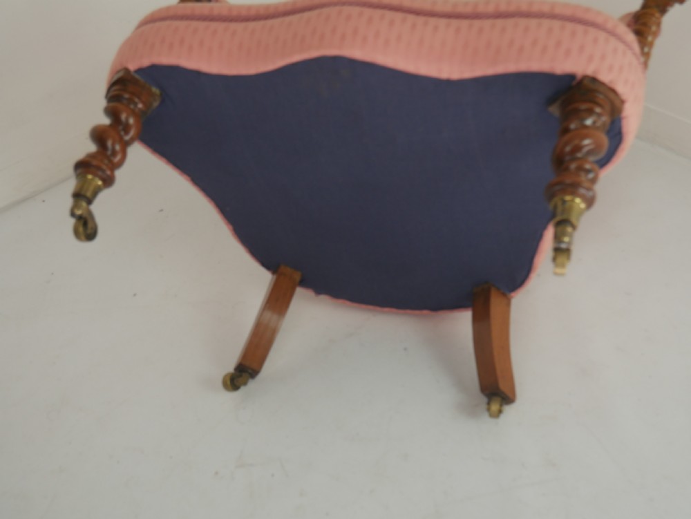 A Victorian armchair upholstered in dusty pink patterned fabric featuring carved walnut barley-twist legs and arm supports set on brass castors. View XI