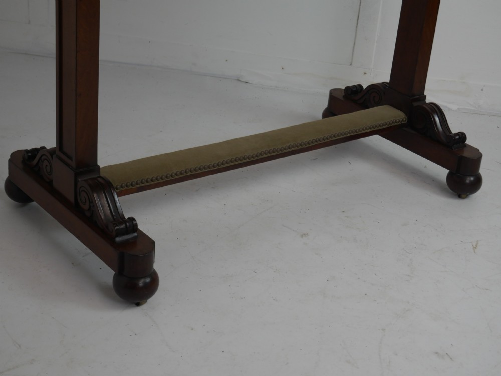 A 19th-century mahogany side table featuring an inset olive green leather top, supported by a trestle base with carved scroll feet. View VI