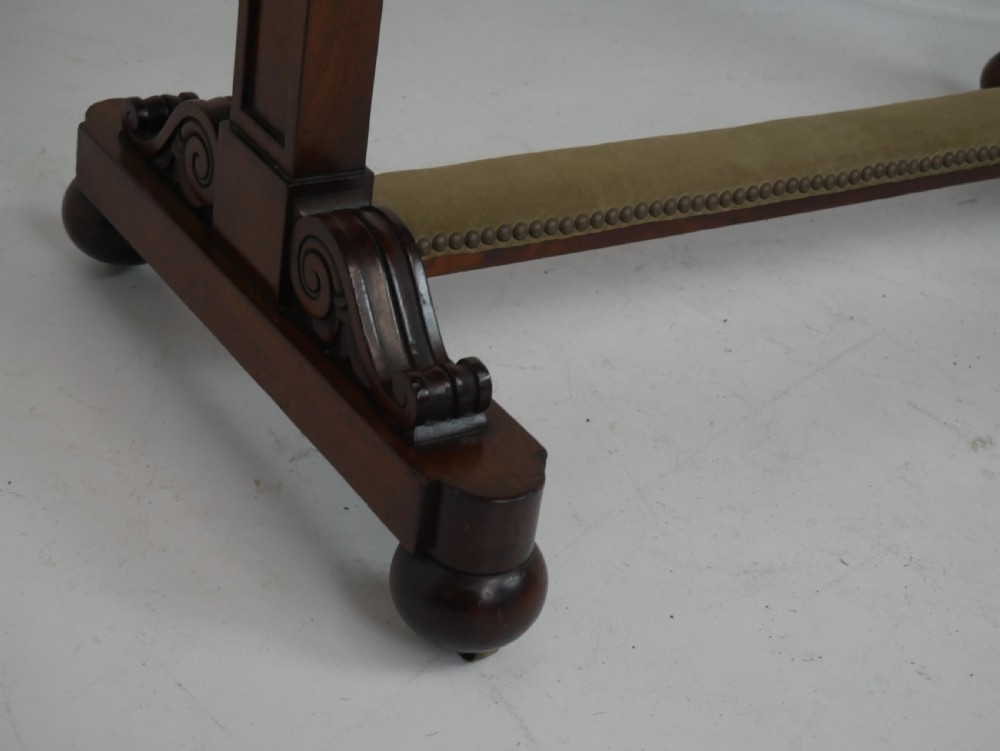 A 19th-century mahogany side table featuring an inset olive green leather top, supported by a trestle base with carved scroll feet. View VII