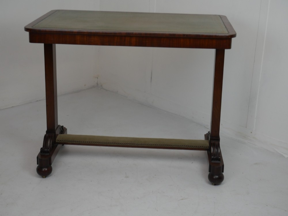 A 19th-century mahogany side table featuring an inset olive green leather top, supported by a trestle base with carved scroll feet. View VIII