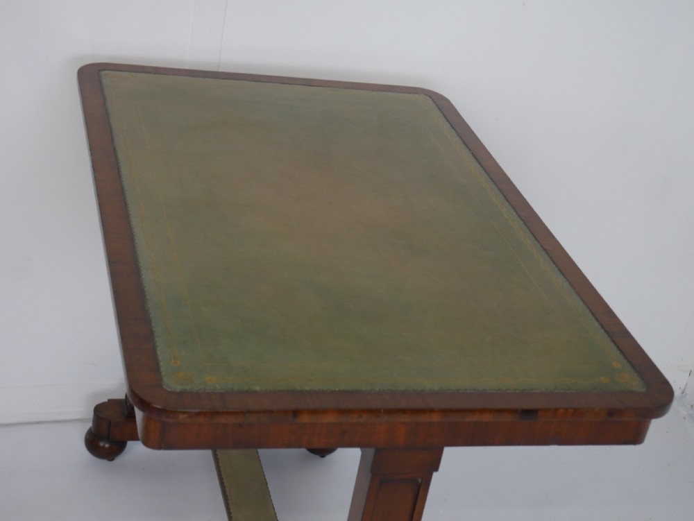A 19th-century mahogany side table featuring an inset olive green leather top, supported by a trestle base with carved scroll feet. View X