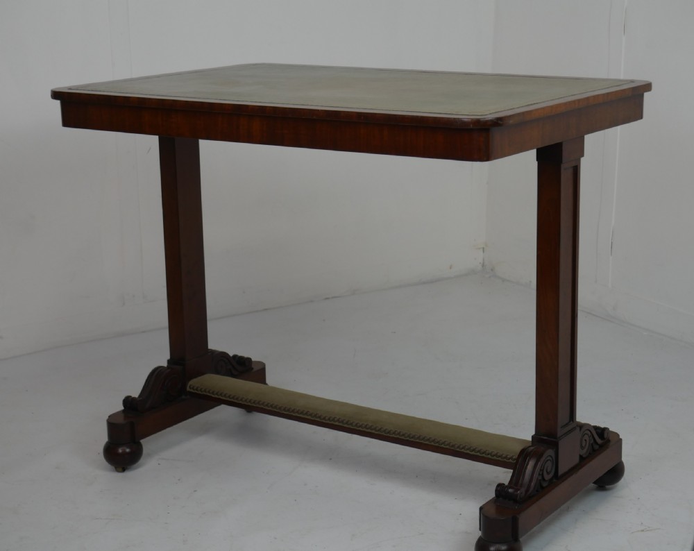 A 19th-century mahogany side table featuring an inset olive green leather top, supported by a trestle base with carved scroll feet. View XII