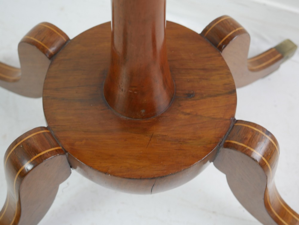 A Regency mahogany sewing table featuring a rectangular top with string inlay, a pleated red fabric work bin below, a turned pedestal support, and four splayed legs with brass castors. View VII