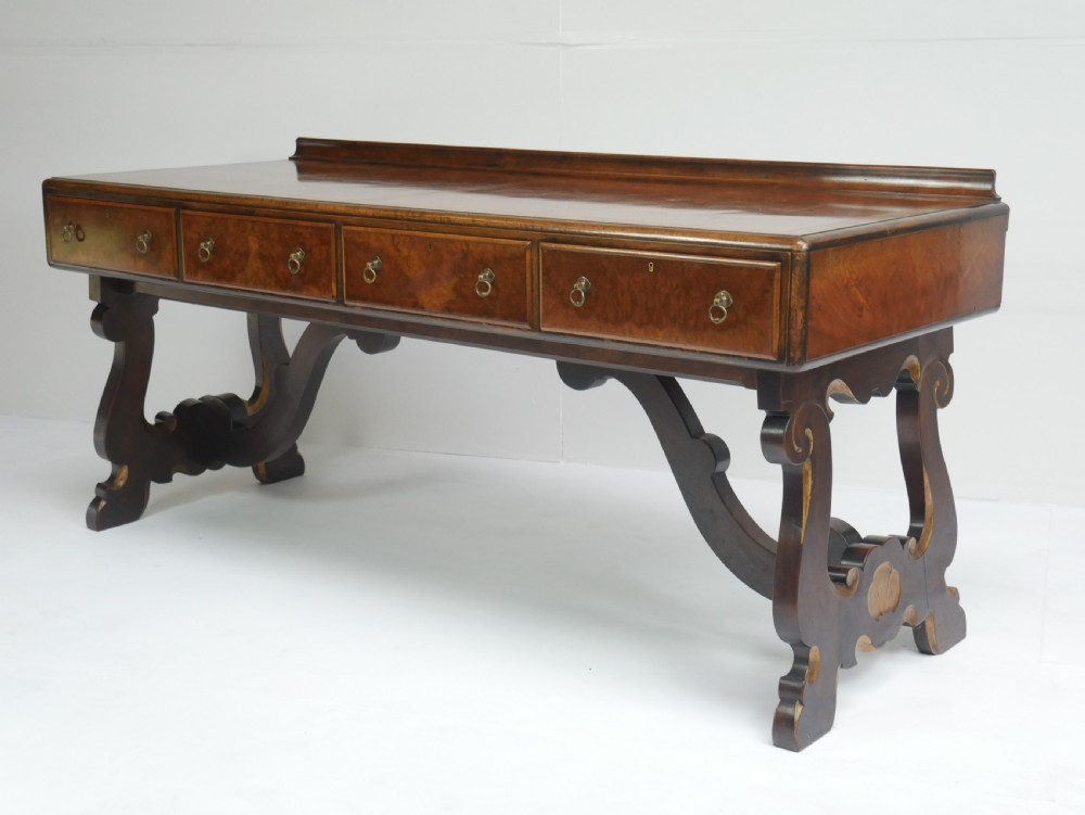 A large antique Scottish mahogany and walnut serving table featuring four brass-handled drawers, carved scroll leg supports, and a low rear gallery back.