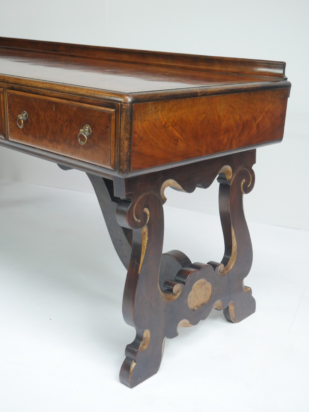 A large antique Scottish mahogany and walnut serving table featuring four brass-handled drawers, carved scroll leg supports, and a low rear gallery back. View V
