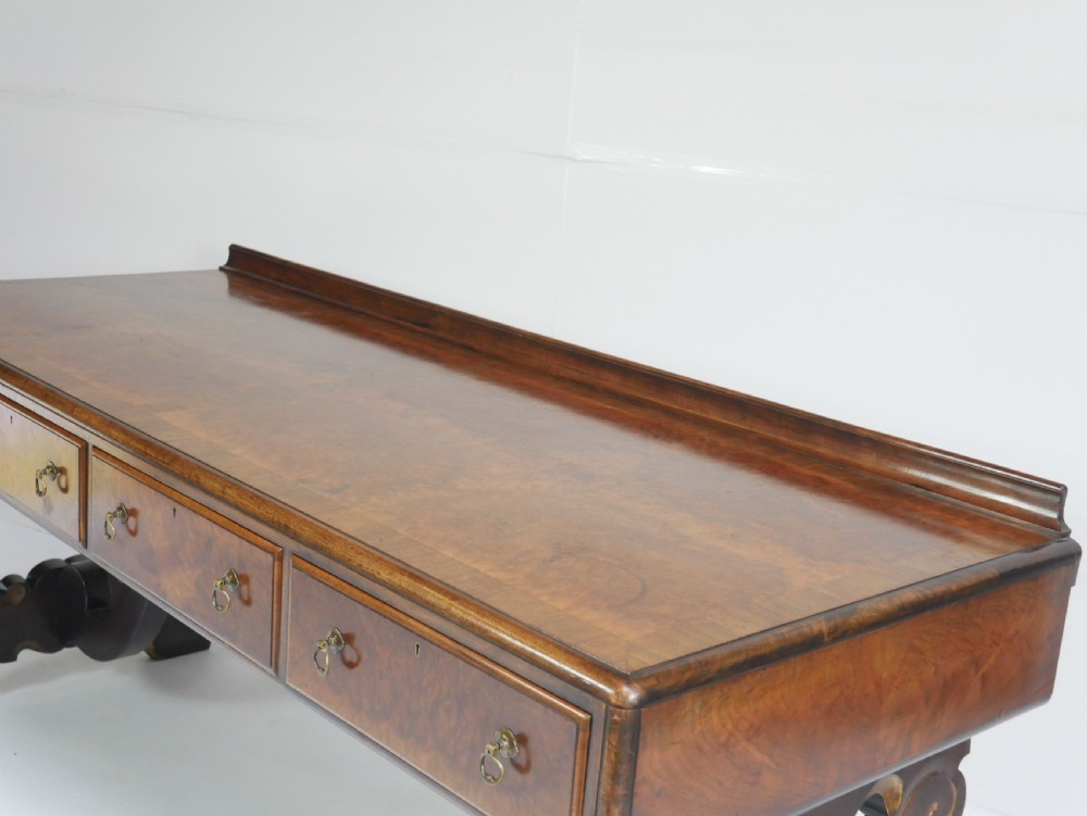 A large antique Scottish mahogany and walnut serving table featuring four brass-handled drawers, carved scroll leg supports, and a low rear gallery back. View XII