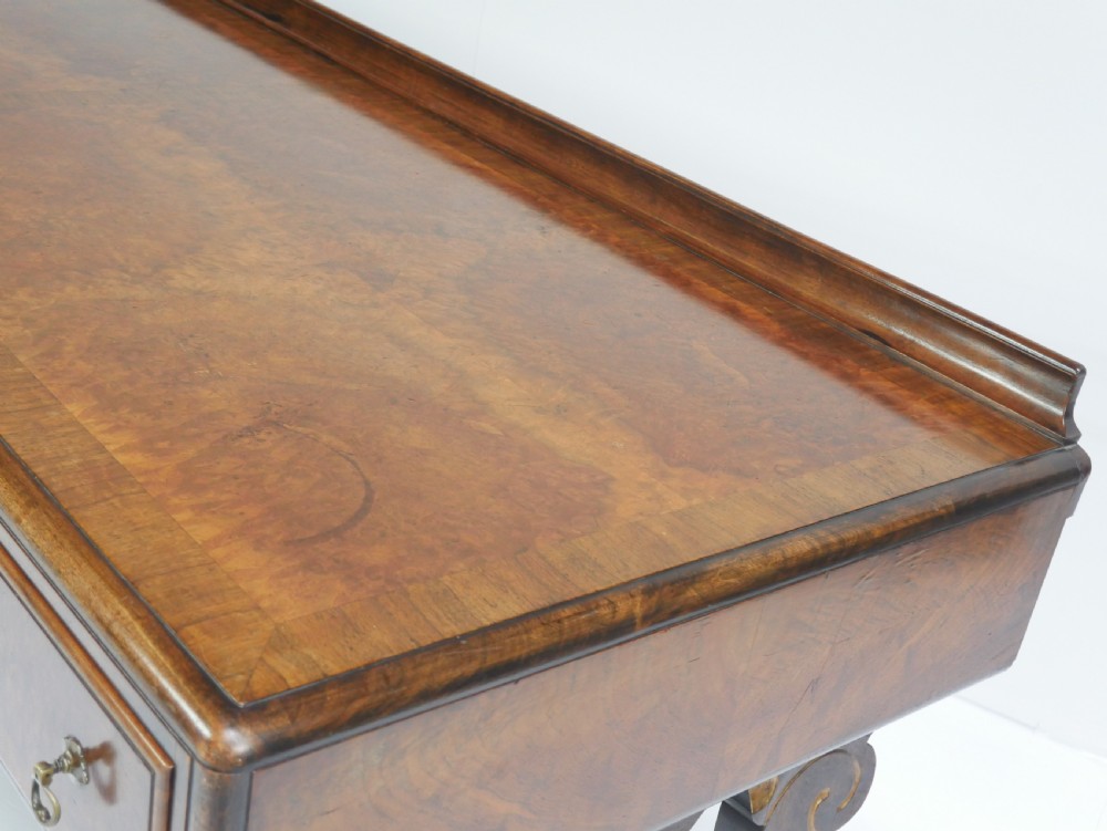 A large antique Scottish mahogany and walnut serving table featuring four brass-handled drawers, carved scroll leg supports, and a low rear gallery back. View XV