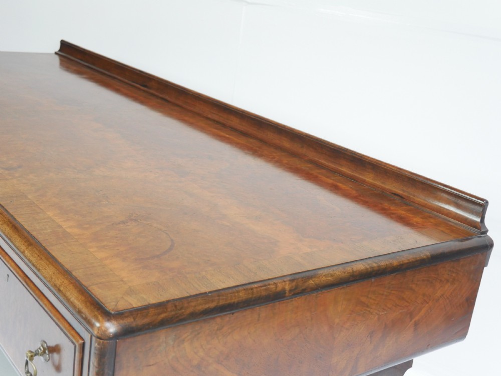 A large antique Scottish mahogany and walnut serving table featuring four brass-handled drawers, carved scroll leg supports, and a low rear gallery back. View XVI
