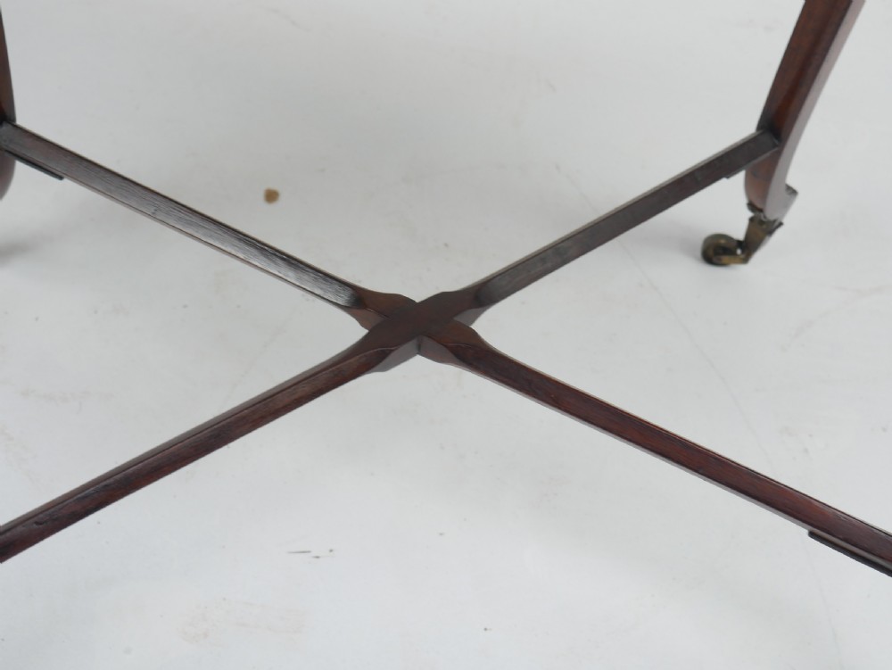 A Sheraton period mahogany occasional table featuring three stacked drawers, canted corners, splayed legs with brass castors, and an X-stretcher. View VI