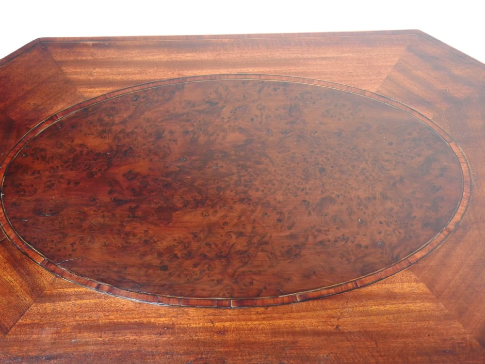 A Sheraton period mahogany occasional table featuring three stacked drawers, canted corners, splayed legs with brass castors, and an X-stretcher. View XII