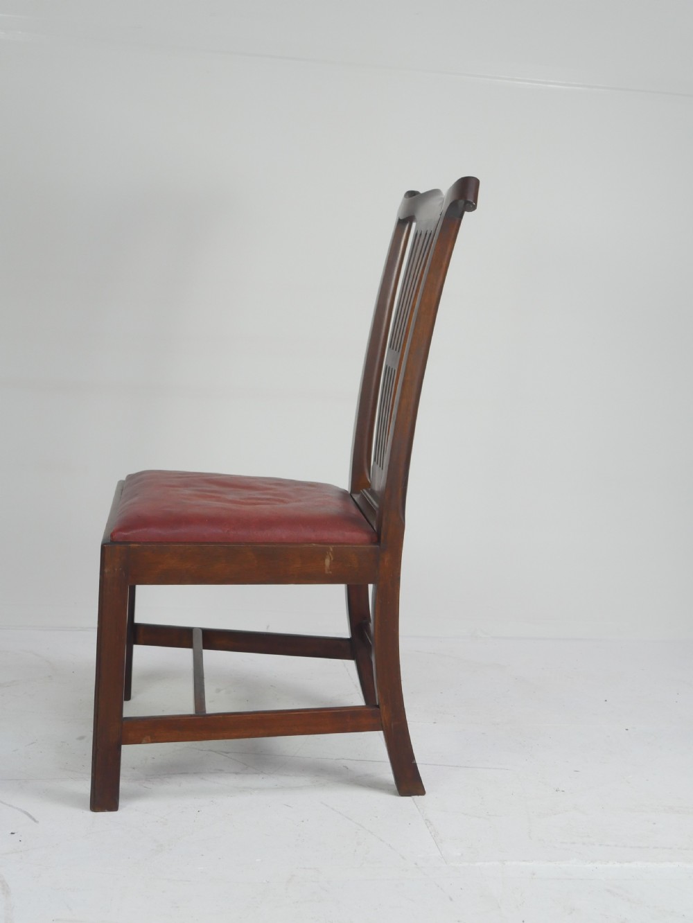A pair of 19th-century mahogany side chairs with pierced back splats, serpentine top rails, straight legs with stretchers, and red leather seats. View IV