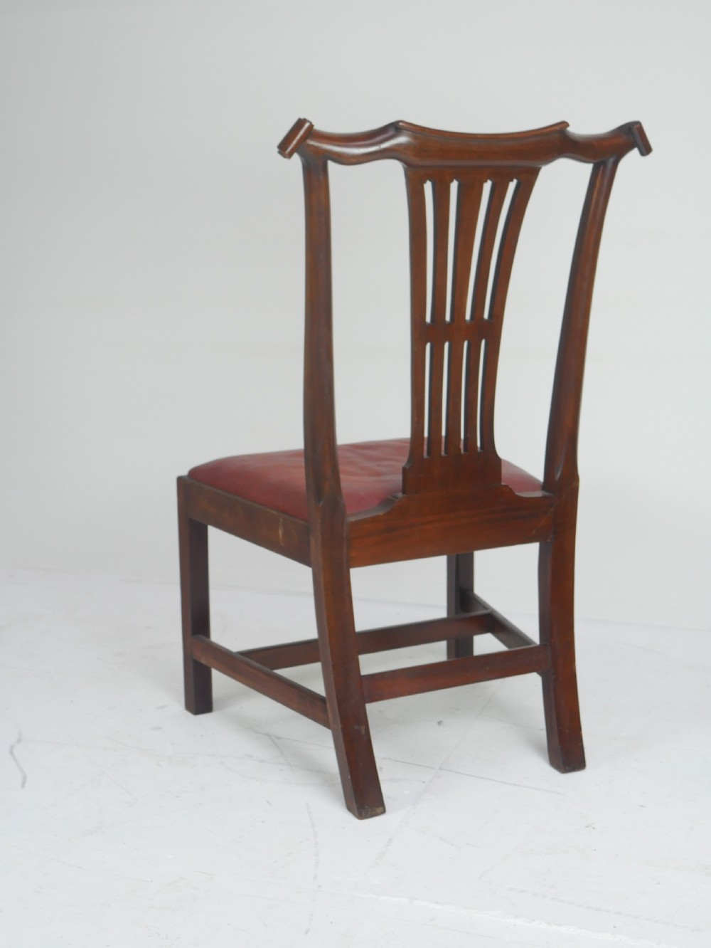 A pair of 19th-century mahogany side chairs with pierced back splats, serpentine top rails, straight legs with stretchers, and red leather seats. View VI