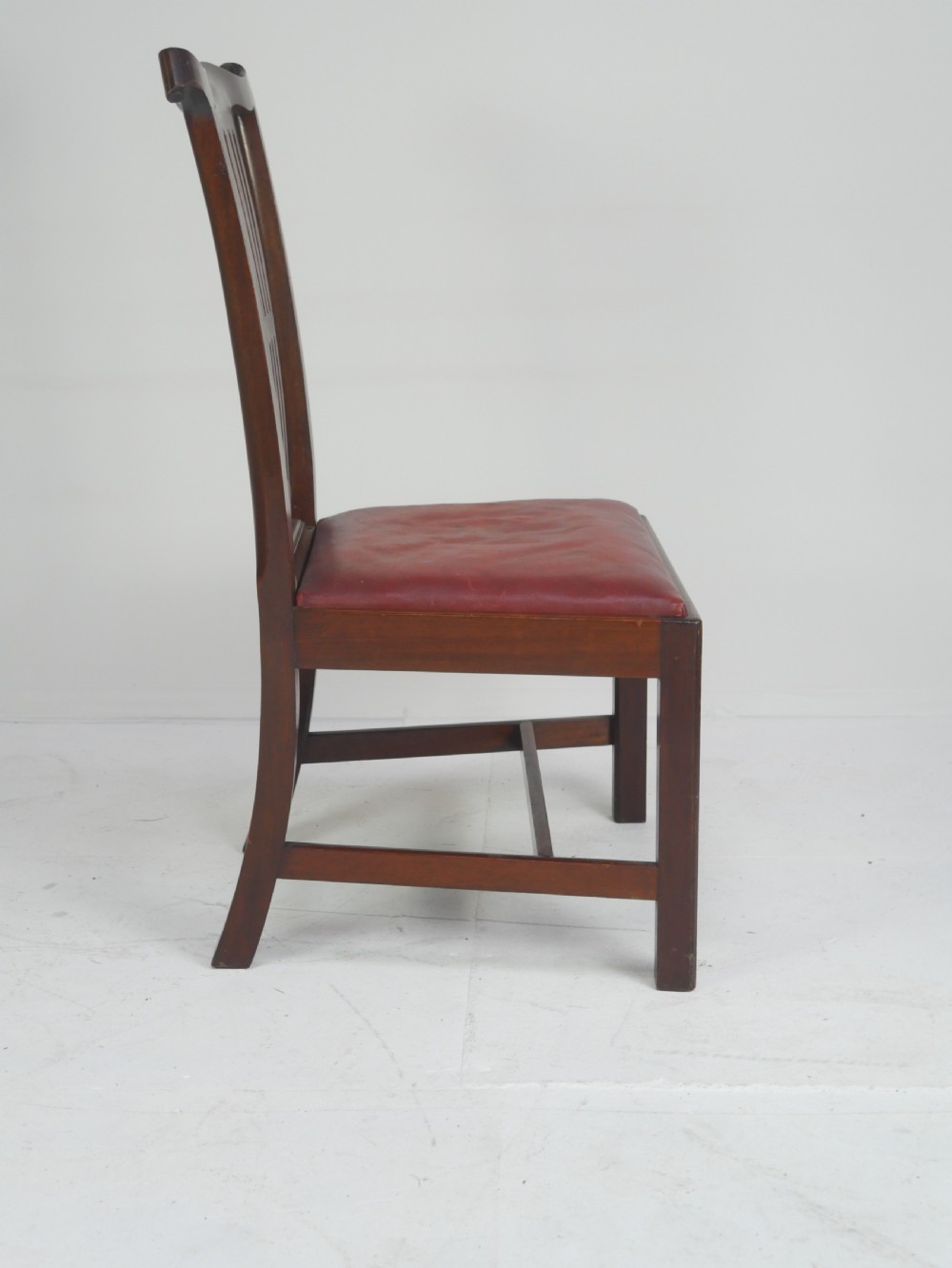 A pair of 19th-century mahogany side chairs with pierced back splats, serpentine top rails, straight legs with stretchers, and red leather seats. View VIII