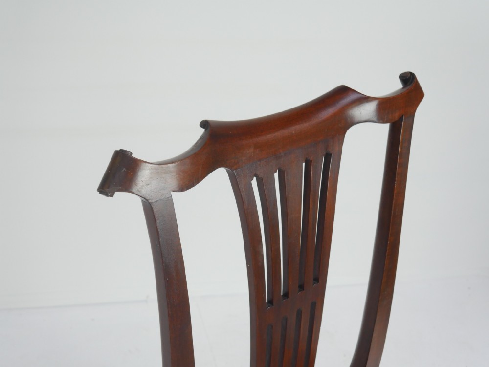 A pair of 19th-century mahogany side chairs with pierced back splats, serpentine top rails, straight legs with stretchers, and red leather seats. View IX
