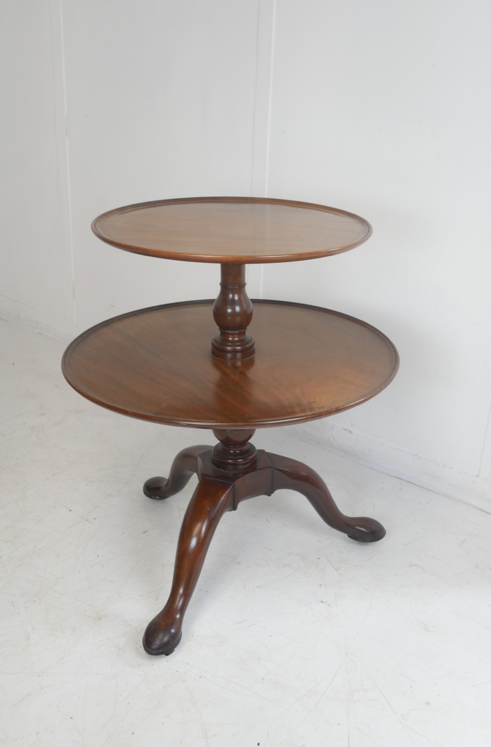 An 18th-century Georgian mahogany two-tier dumb waiter table with two graduated circular tray-moulded platforms on a turned baluster column and tripod pad feet.