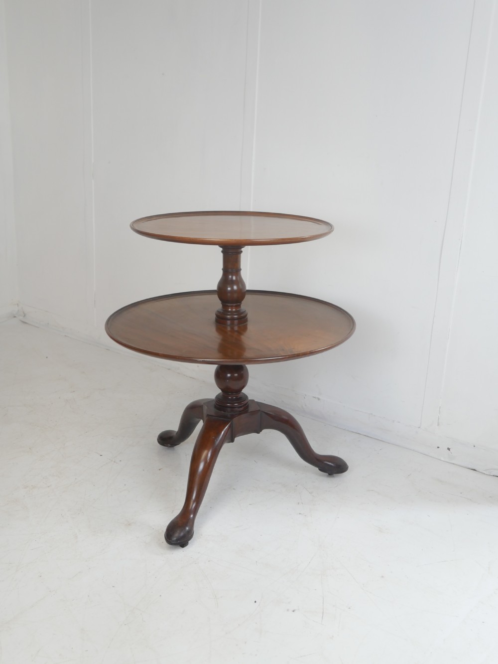 An 18th-century Georgian mahogany two-tier dumb waiter table with two graduated circular tray-moulded platforms on a turned baluster column and tripod pad feet. View V