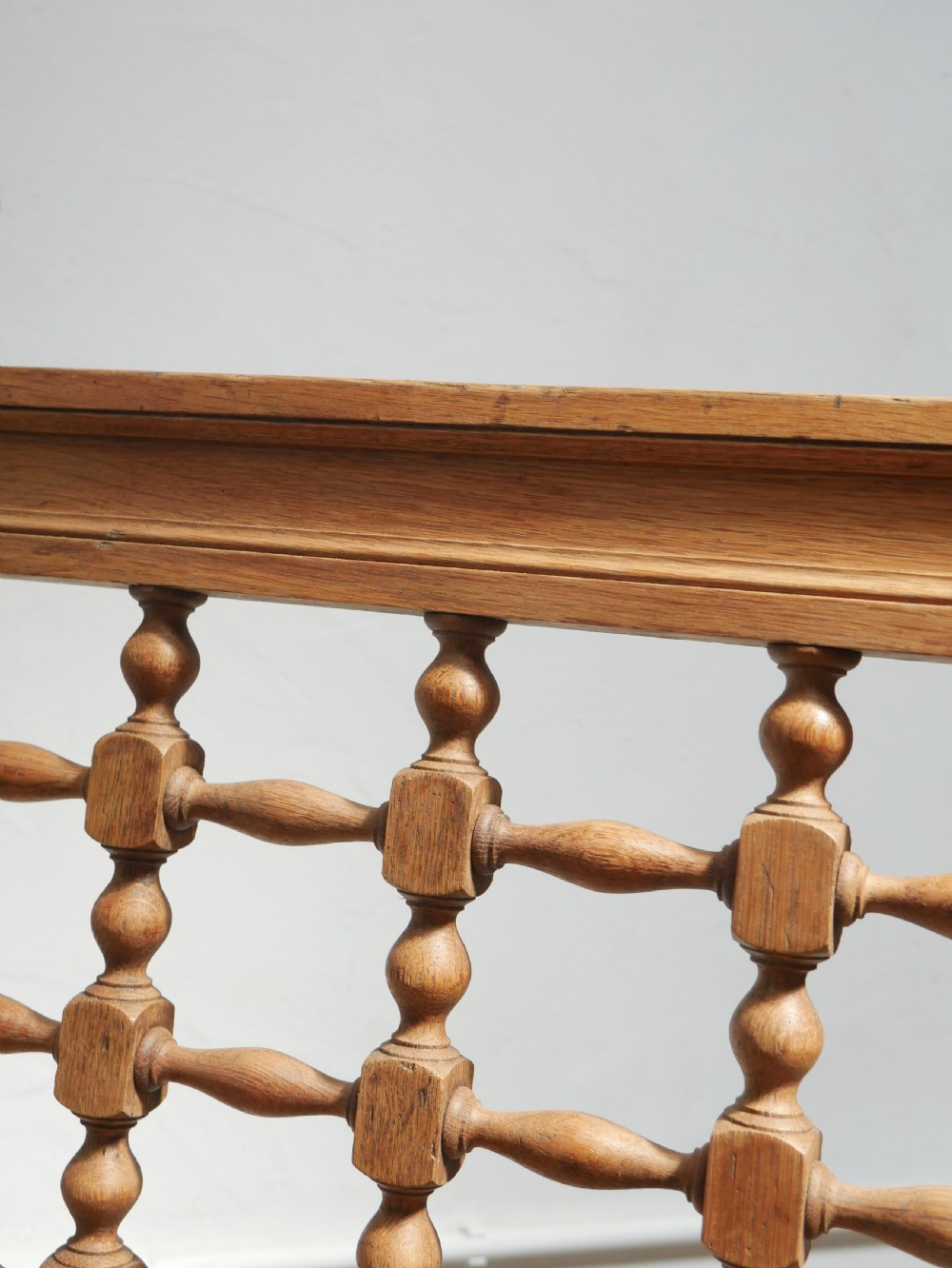 An antique light oak hall settle featuring a turned spindle lattice backrest, sweeping curved armrests, and a lift-up storage seat box. View V