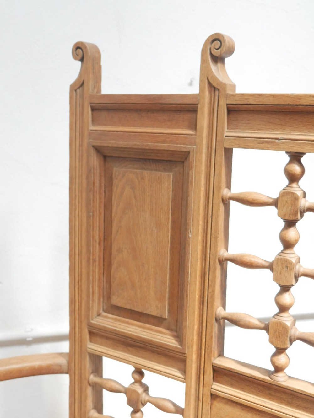 An antique light oak hall settle featuring a turned spindle lattice backrest, sweeping curved armrests, and a lift-up storage seat box. View VI