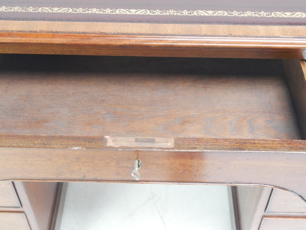 A Georgian mahogany kneehole desk featuring multiple side drawers with brass ring handles and a plinth base. View VII