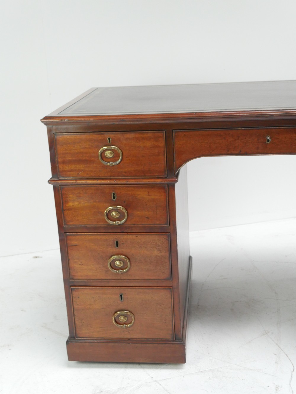 A Georgian mahogany kneehole desk featuring multiple side drawers with brass ring handles and a plinth base. View IX