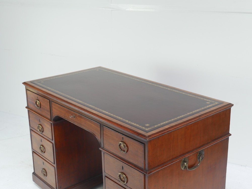 A Georgian mahogany kneehole desk featuring multiple side drawers with brass ring handles and a plinth base. View II