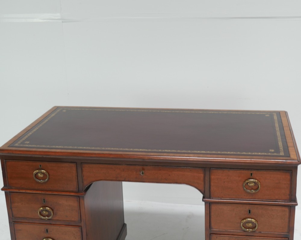 A Georgian mahogany kneehole desk featuring multiple side drawers with brass ring handles and a plinth base. View XIV