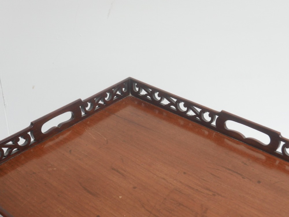 An early 20th-century dark mahogany butler tray table with a pierced fretwork gallery rim mounted on a four-legged wooden stand. View III