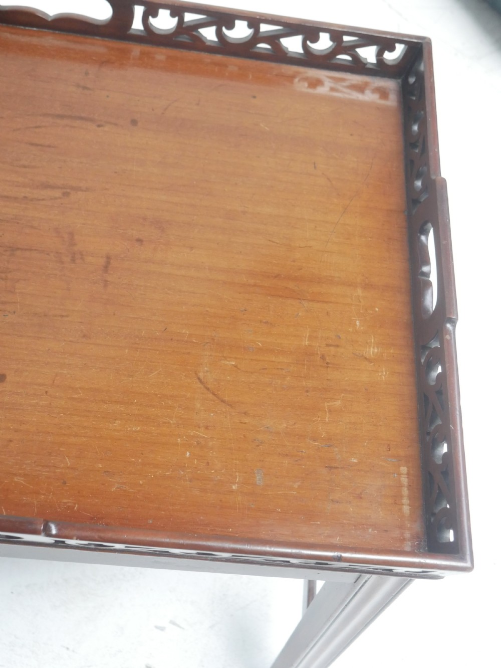 An early 20th-century dark mahogany butler tray table with a pierced fretwork gallery rim mounted on a four-legged wooden stand. View V