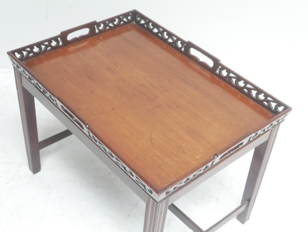 An early 20th-century dark mahogany butler tray table with a pierced fretwork gallery rim mounted on a four-legged wooden stand. View VI