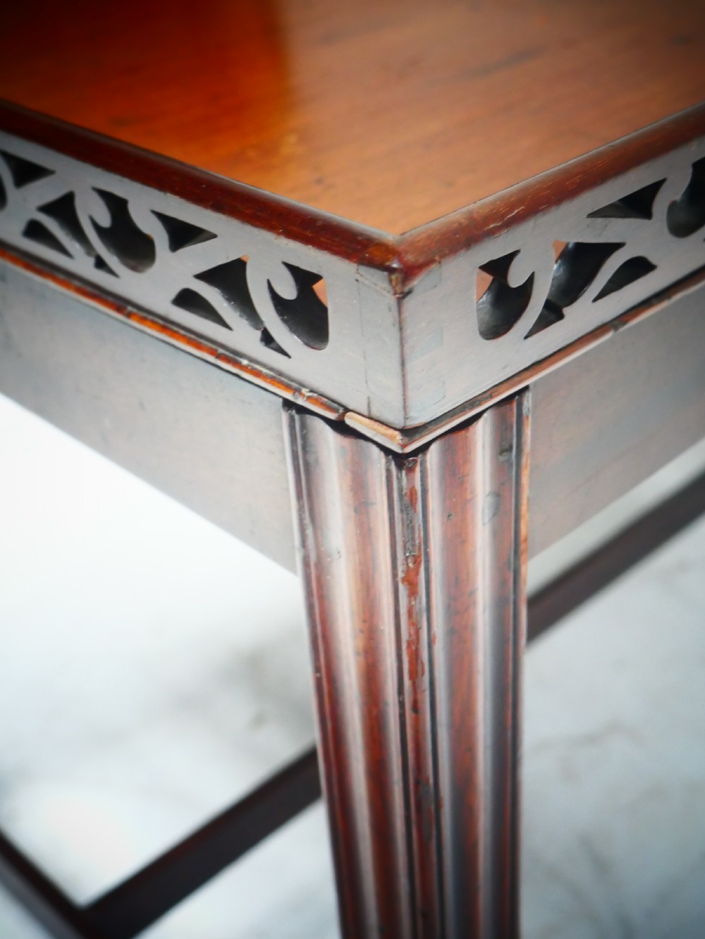 An early 20th-century dark mahogany butler tray table with a pierced fretwork gallery rim mounted on a four-legged wooden stand. View IX